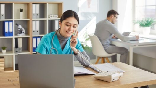 Female nurse practitioner scheduling patients and male nurse practitioner working at desk.