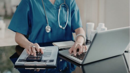 female nurse practitioner using laptop and calculator