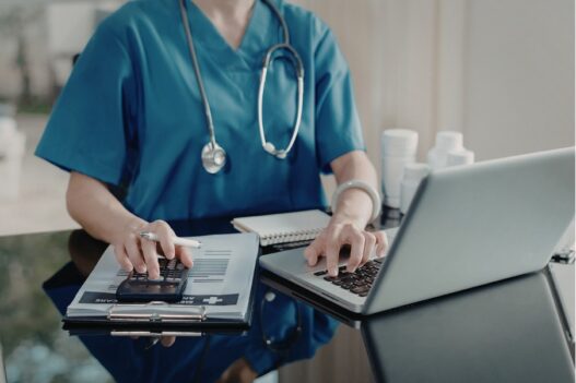 female nurse practitioner using laptop and calculator