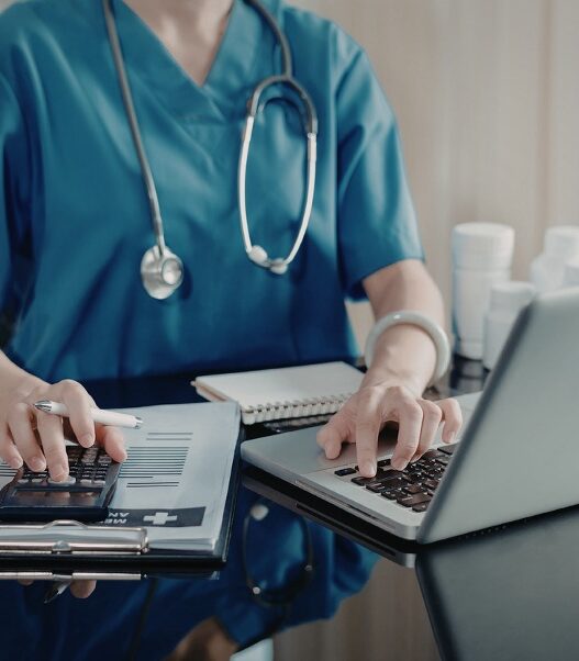 female nurse practitioner using laptop and calculator