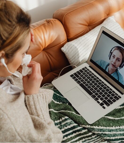 female patient using telehealth video call with female nurse on laptop from home